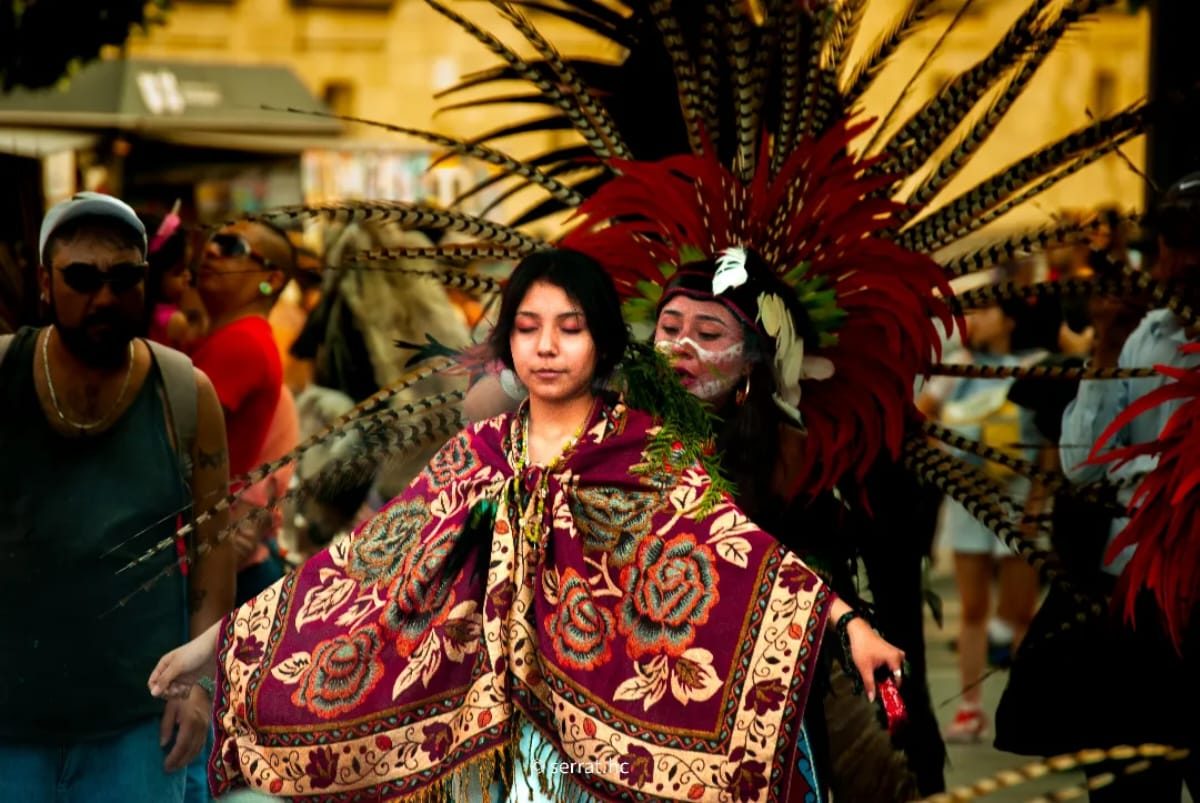 Danzantes con penachos de plumas rojas y rebozo bordado durante una danza tradicional